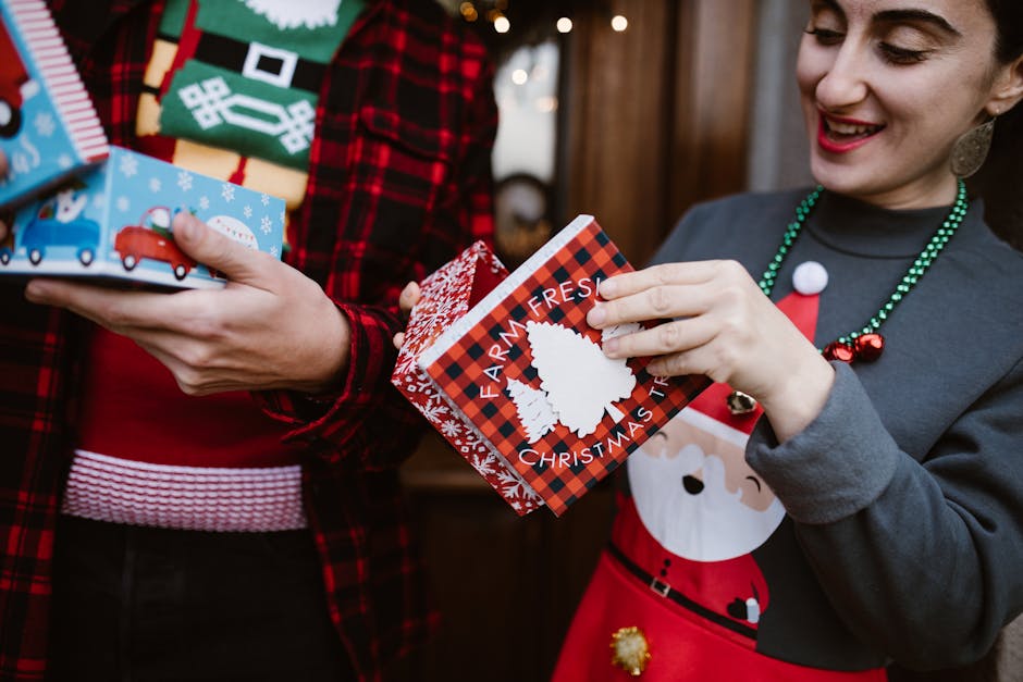 Two people joyfully exchanging Christmas gifts, each bearing holiday-themed designs, indoors.