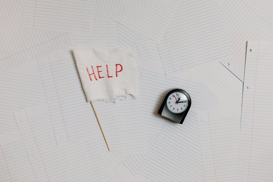 A flat lay image depicting stress and overwork with a help flag and clock on papers.