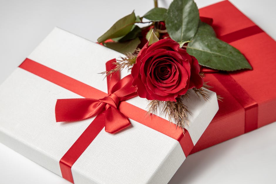 Close-up of red rose atop elegantly wrapped gift boxes with red ribbons, perfect for gift-giving occasions.