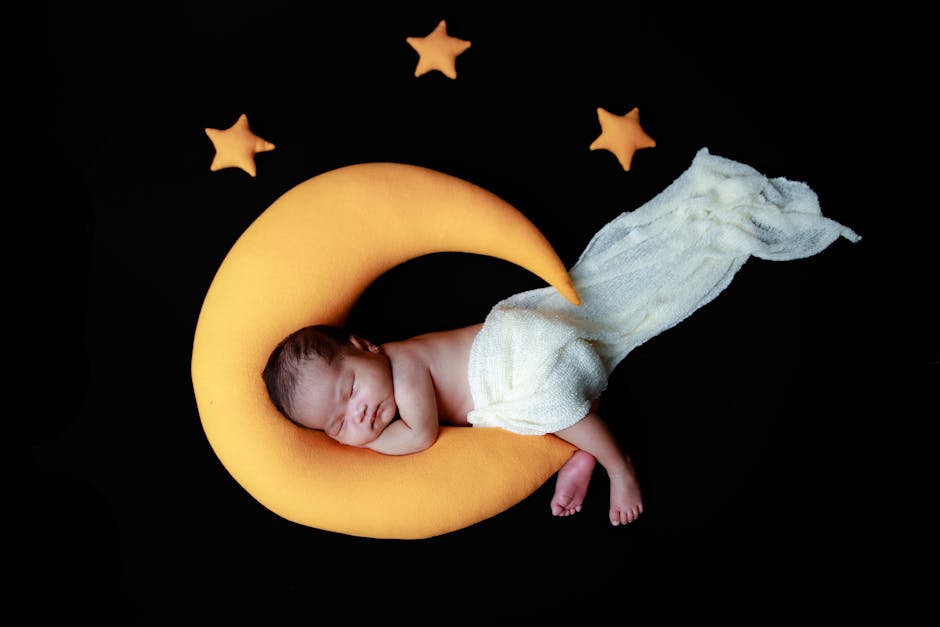 Adorable newborn baby asleep on a moon pillow surrounded by stars in a peaceful setting.