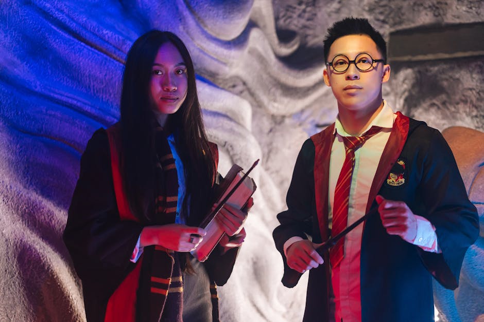 Two adults in wizard costumes holding magic wands in an indoor setting.