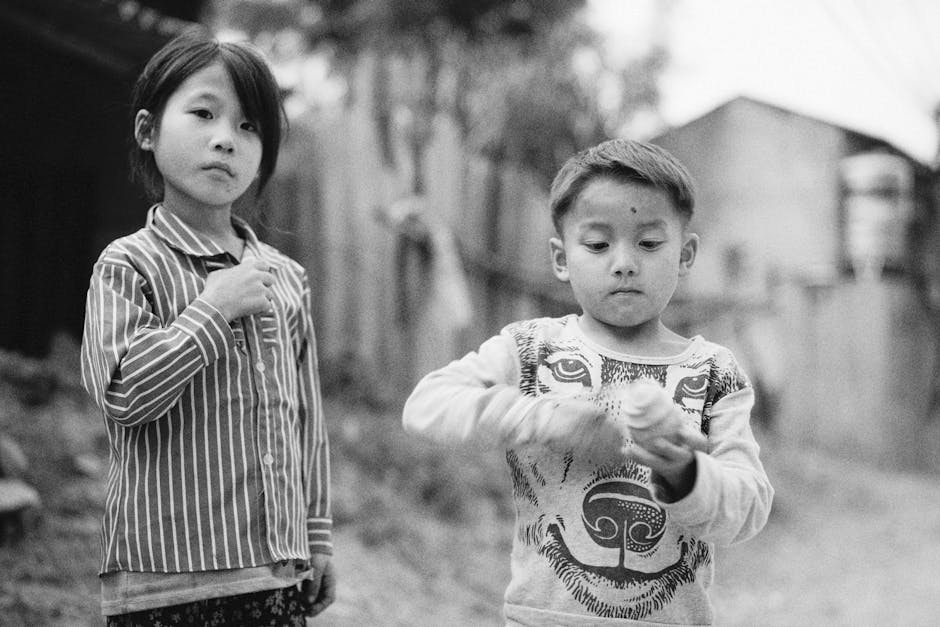 Two children in an outdoor setting, captured in a candid black and white portrait.