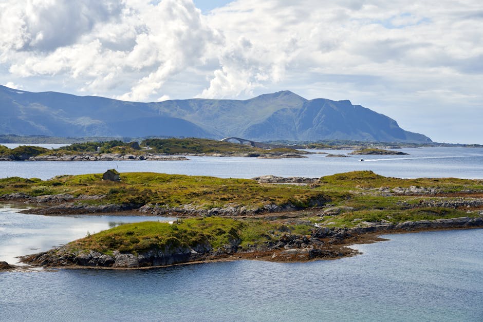 Breathtaking coastal landscape with green islands and mountainous backdrop under a cloudy sky.