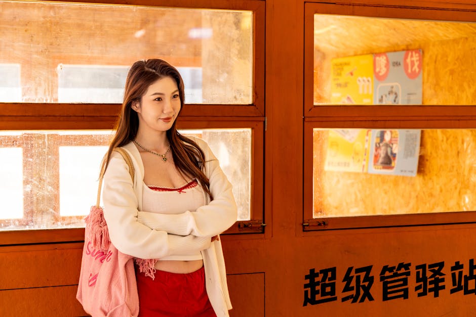 Young woman standing indoors by bright windows, exuding confidence and warmth.