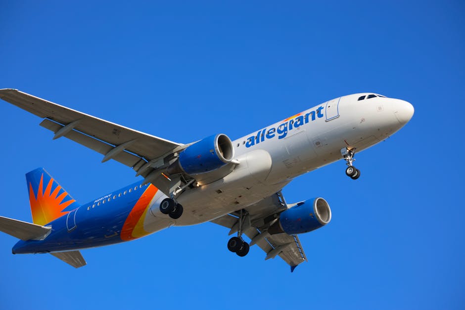 A commercial airliner flying with a clear blue sky backdrop, symbolizing air travel.