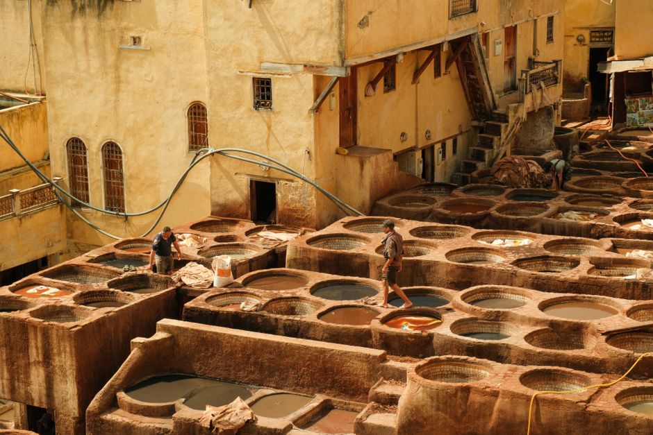 Aerial view of workers at a classic leather tannery in Fes under sunny skies.