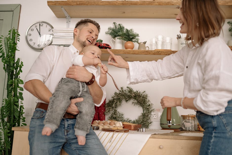 A joyful family moment capturing parents and baby in a cozy kitchen setting.
