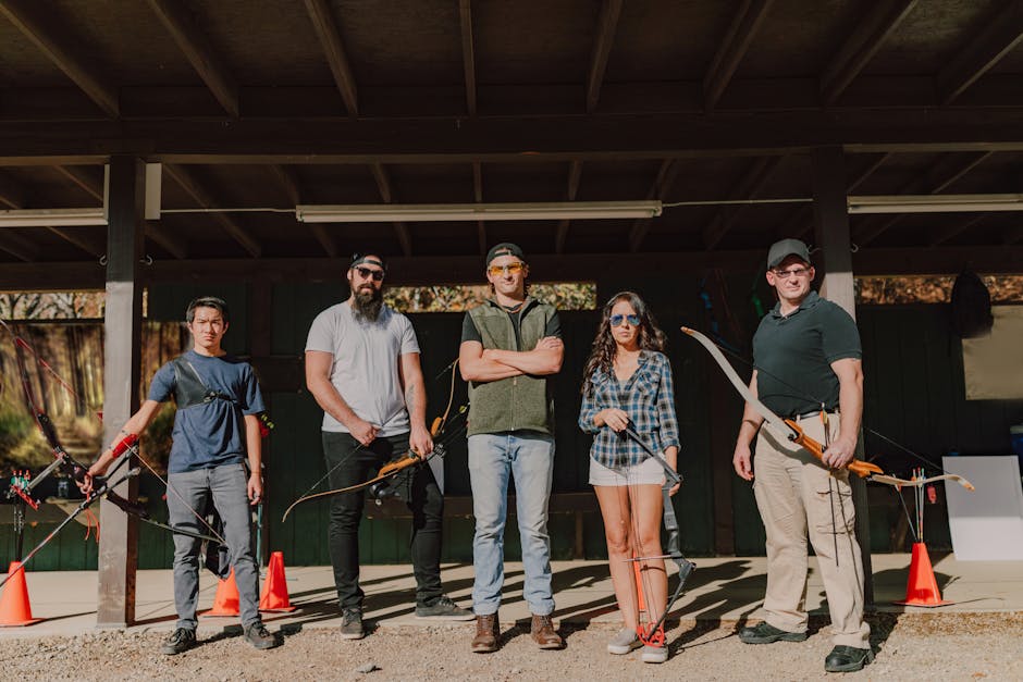 A group of five adults practicing archery outdoors during the day.