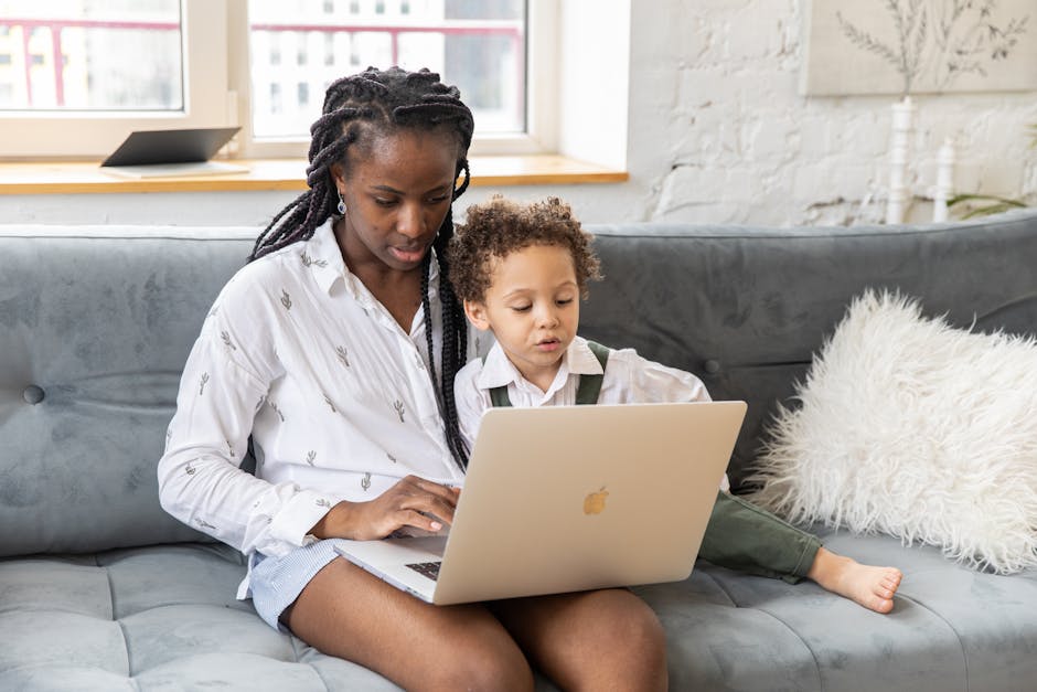 Mother and child bonding while using a laptop on the couch in a cozy home setting.